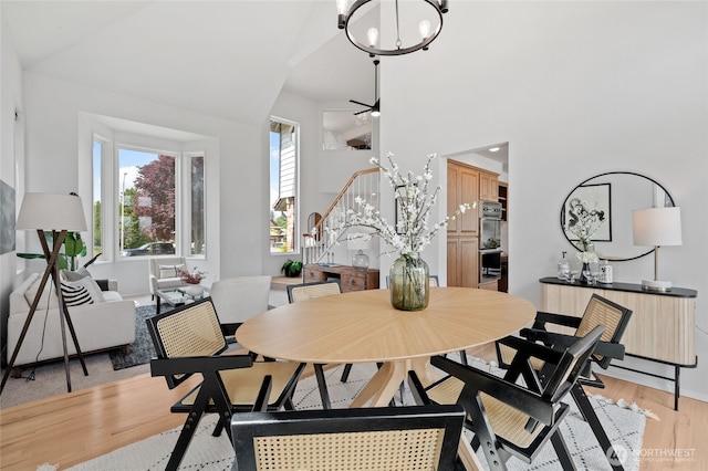 19724 Island Pkwy E, Lake Tapps, WA 98391 - dining room with healthy amount of natural light, light wood finished floors, a chandelier, stairway, and a towering ceiling