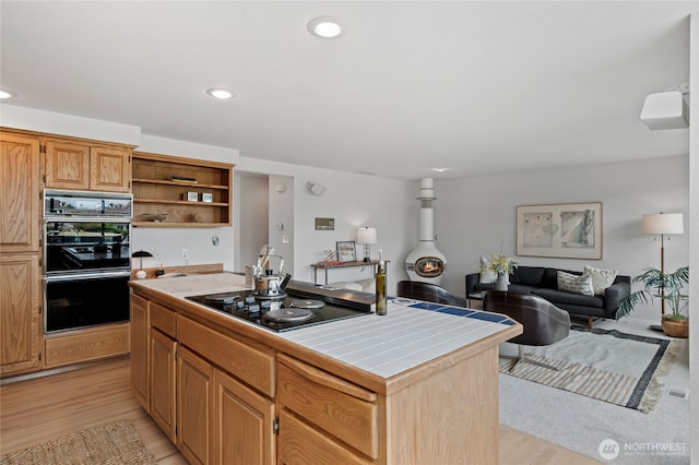 19724 Island Pkwy E, Lake Tapps, WA 98391 - kitchen with black appliances, tile counters, open shelves, light wood-type flooring, and a kitchen island