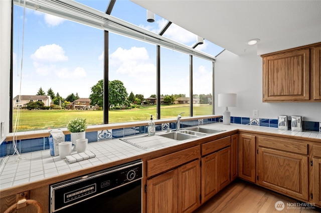 19724 Island Pkwy E, Lake Tapps, WA 98391 - kitchen with dishwasher, tile countertops, light wood-style flooring, and brown cabinetry