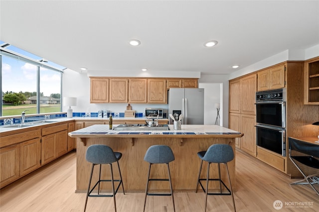 19724 Island Pkwy E, Lake Tapps, WA 98391 - kitchen featuring stainless steel refrigerator with ice dispenser, a kitchen breakfast bar, light countertops, light wood-style floors, and recessed lighting