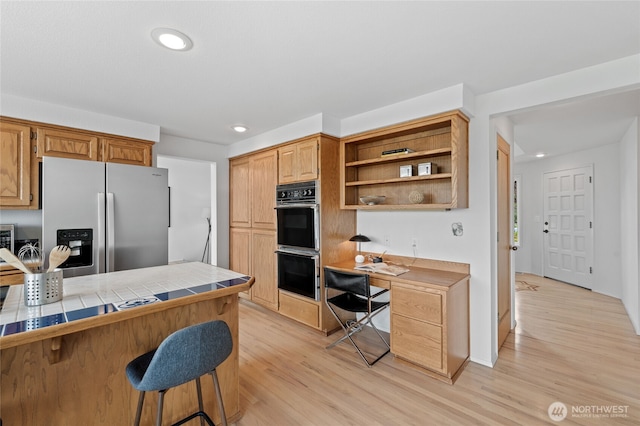 19724 Island Pkwy E, Lake Tapps, WA 98391 - kitchen featuring stainless steel fridge, tile counters, a kitchen bar, light wood-style flooring, and open shelves