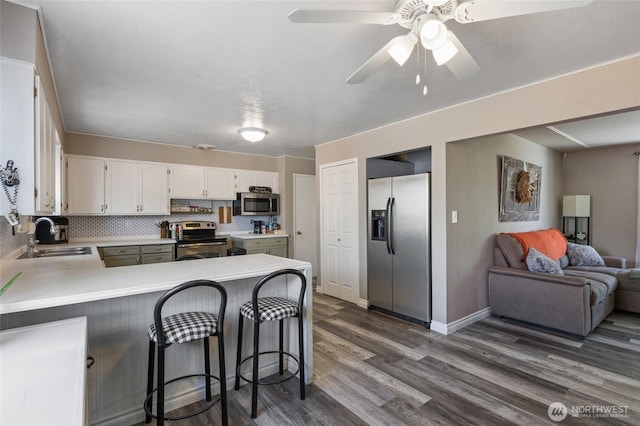 863 N Vista Dr, Moses Lake, WA 98837 - kitchen featuring appliances with stainless steel finishes, dark wood-style floors, a peninsula, open floor plan, and light countertops