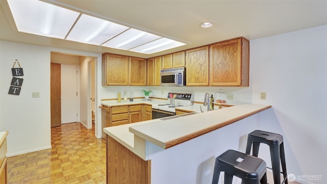 16159 SE 33rd Cir Unit 603, Bellevue, WA 98008 - kitchen featuring white electric stove, stainless steel microwave, a breakfast bar, light countertops, and a peninsula