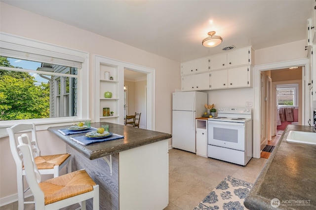 515 N 122nd St, Seattle, WA 98133 - kitchen featuring white appliances, white cabinets, dark countertops, a kitchen breakfast bar, and open shelves