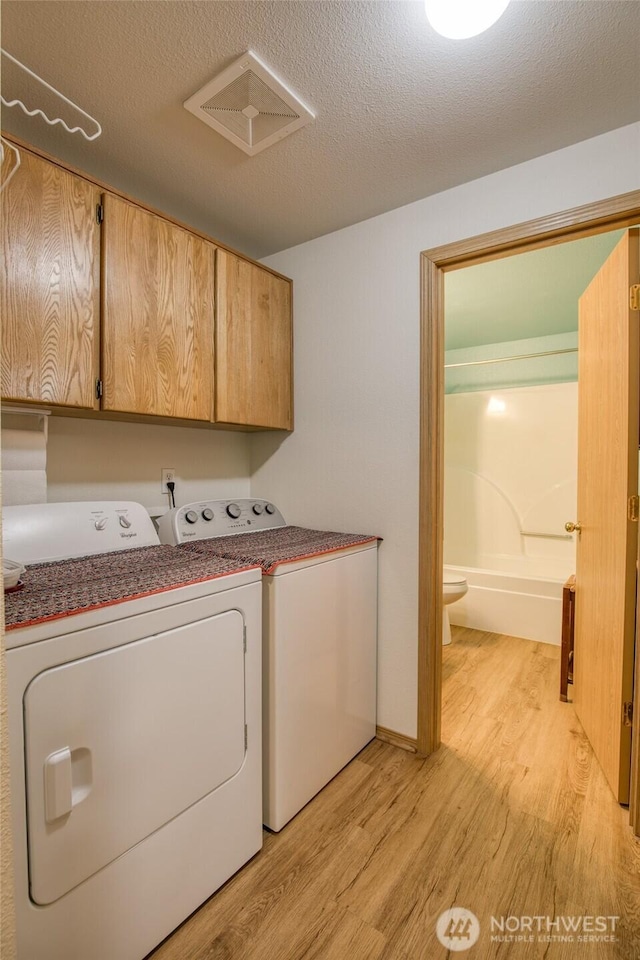 199 Ocean Blvd, Ocean Shores, WA 98569 - laundry area with independent washer and dryer, light wood-style flooring, cabinet space, and a textured ceiling