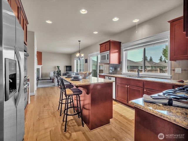 4021 220th St SE, Bothell, WA 98021 - kitchen featuring appliances with stainless steel finishes, light stone counters, dark brown cabinets, light wood finished floors, and a center island