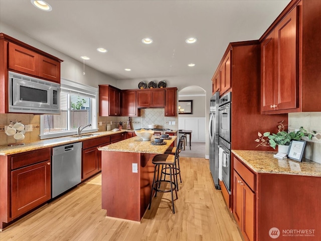 4021 220th St SE, Bothell, WA 98021 - kitchen with stainless steel appliances, a breakfast bar area, light wood-type flooring, tasteful backsplash, and arched walkways