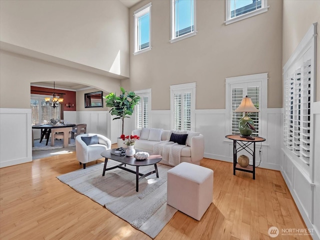 4021 220th St SE, Bothell, WA 98021 - living area with a towering ceiling, a chandelier, arched walkways, wainscoting, and light wood-style floors