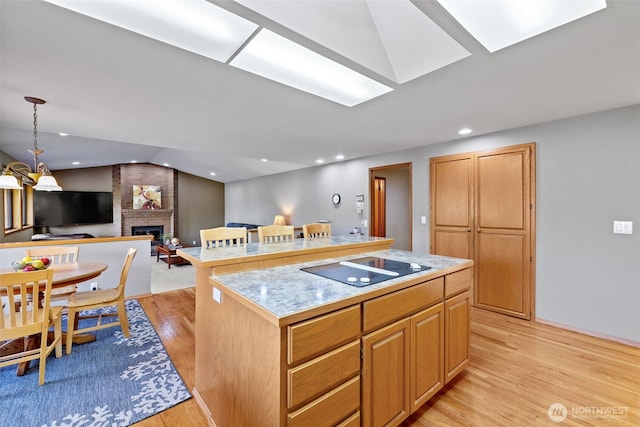7617 160th St SE, Snohomish, WA 98296 - kitchen featuring black electric stovetop, a fireplace, light wood-style flooring, a center island, and light countertops