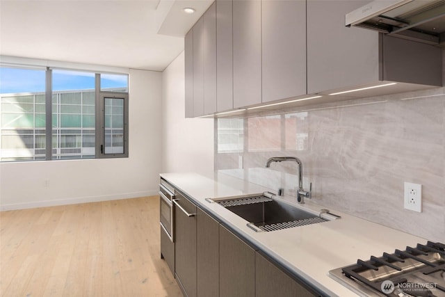 2510 6th Ave Unit 809, Seattle, WA 98121 - kitchen with under cabinet range hood, backsplash, light countertops, and light wood-type flooring