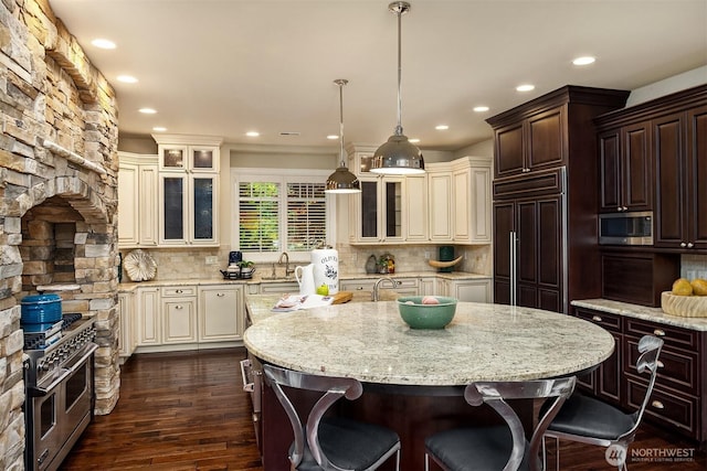 67 Cascade Ky, Bellevue, WA 98006 - kitchen featuring premium appliances, cream cabinetry, dark wood-type flooring, recessed lighting, and a kitchen breakfast bar