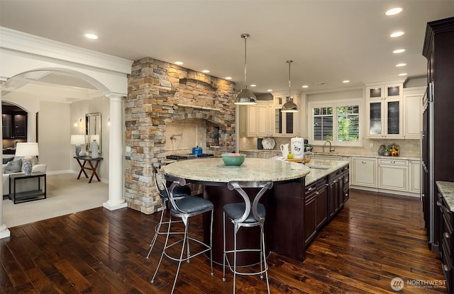 67 Cascade Ky, Bellevue, WA 98006 - kitchen featuring dark wood finished floors, recessed lighting, glass insert cabinets, a breakfast bar, and a kitchen island with sink