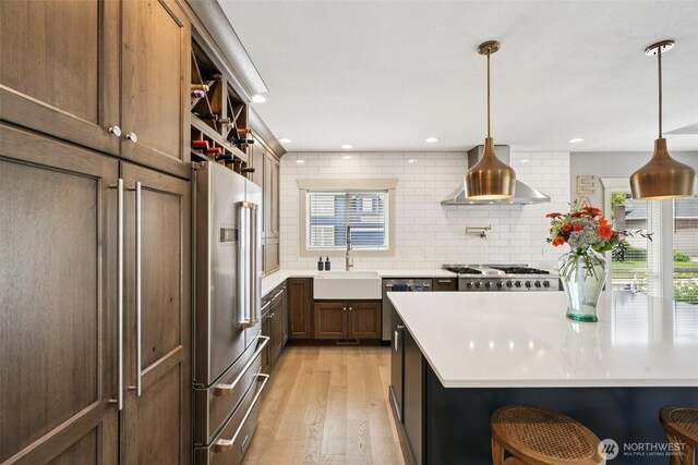 4706 NE 137th St NE, Vancouver, WA 98686 - kitchen with stainless steel appliances, light wood finished floors, backsplash, light countertops, and wall chimney exhaust hood