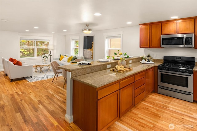 5235 11th Ave NE Unit A, Seattle, WA 98105 - kitchen with stainless steel appliances, open floor plan, a peninsula, light wood-type flooring, and recessed lighting