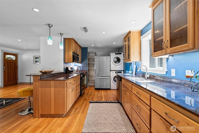 19515 7th Ave NE, Shoreline, WA 98155 - kitchen featuring stainless steel appliances, stacked washer and clothes dryer, a kitchen bar, light wood finished floors, and recessed lighting