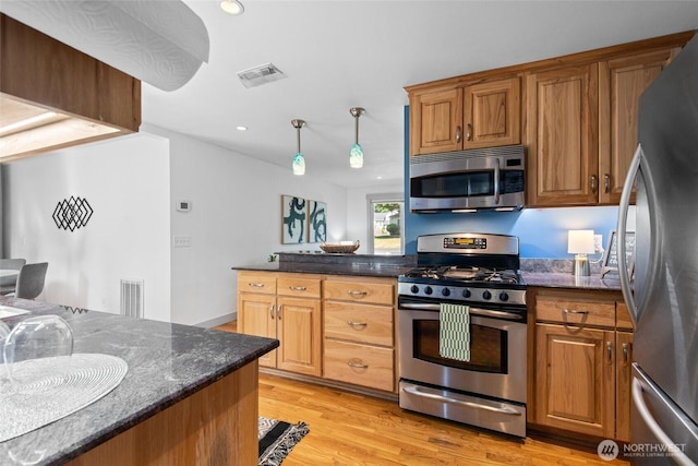 19515 7th Ave NE, Shoreline, WA 98155 - kitchen featuring appliances with stainless steel finishes, light wood finished floors, dark stone countertops, recessed lighting, and brown cabinetry