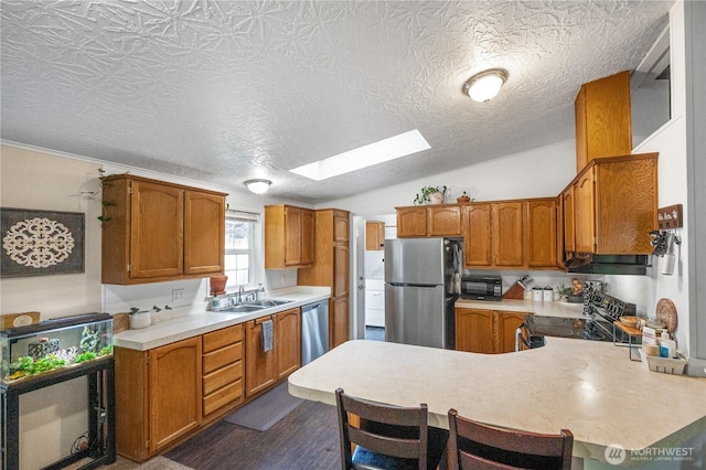 492 Hilltop Dr, Sedro Woolley, WA 98284 - kitchen featuring stainless steel appliances, a skylight, light countertops, a peninsula, and brown cabinetry