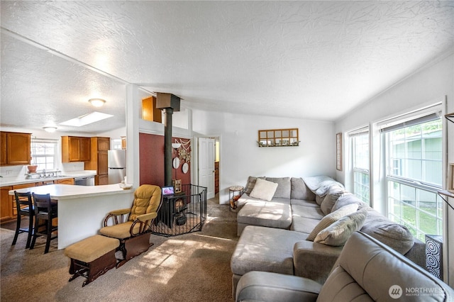 492 Hilltop Dr, Sedro Woolley, WA 98284 - carpeted living area featuring a wood stove, vaulted ceiling, a textured ceiling, and a skylight