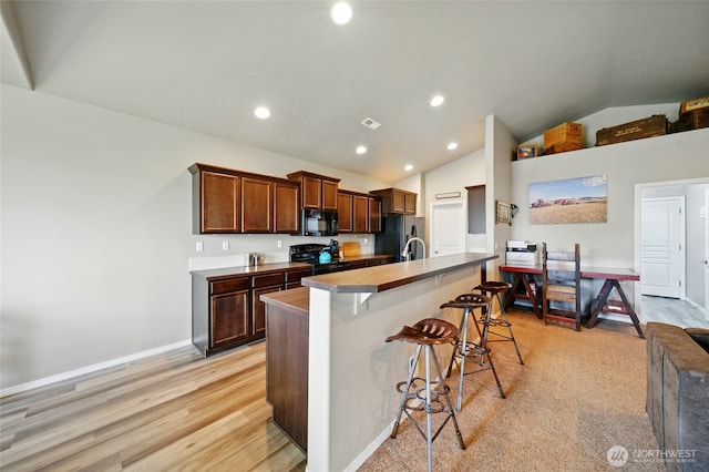 2134 Alco Ave, Walla Walla, WA 99362 - kitchen with black appliances, lofted ceiling, a breakfast bar area, an island with sink, and recessed lighting
