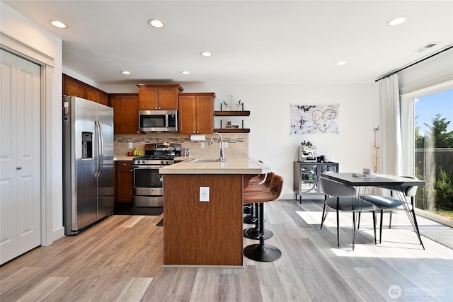 6672 Udall Pl SE, Auburn, WA 98092 - kitchen with stainless steel appliances, light countertops, a kitchen bar, light wood-type flooring, and recessed lighting