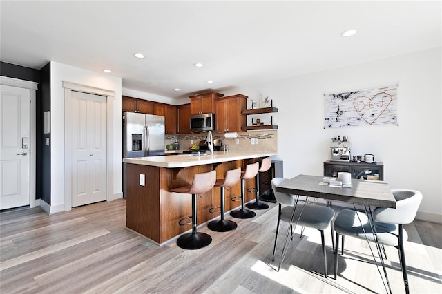6672 Udall Pl SE, Auburn, WA 98092 - kitchen with stainless steel appliances, a peninsula, light countertops, light wood-style floors, and a kitchen bar