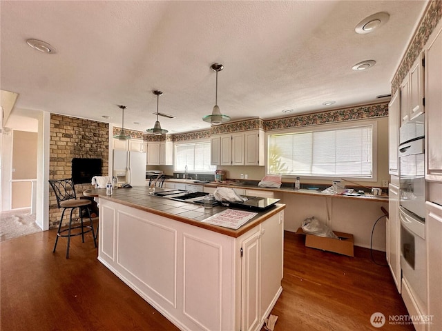 1445 SW 296th St, Federal Way, WA 98023 - kitchen with white appliances, dark wood-style flooring, pendant lighting, a kitchen island, and tile countertops