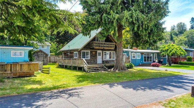 2111 Maple St, Point Roberts, WA 98281 - view of front of house with a storage shed, a front yard, stone siding, a metal roof, and a deck