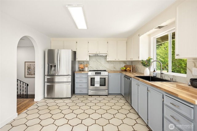 10376 NE Winthers Rd, Bainbridge Island, WA 98110 - kitchen with appliances with stainless steel finishes, wood counters, backsplash, arched walkways, and light floors
