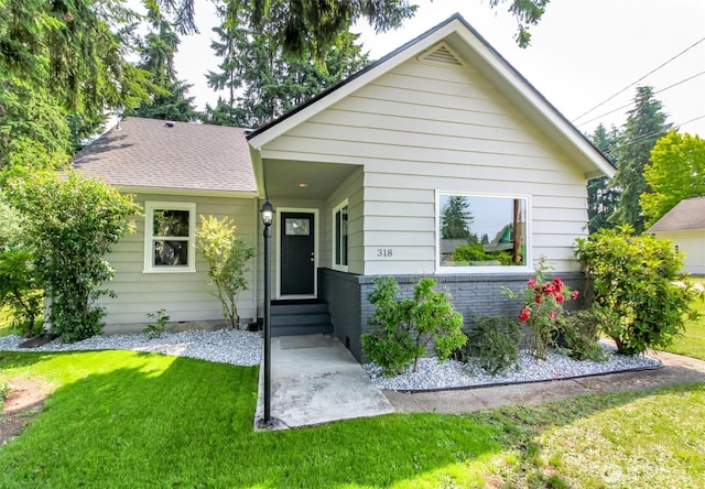 318 Mill Ave SE, Orting, WA 98360 - bungalow with a front lawn, entry steps, a shingled roof, and brick siding