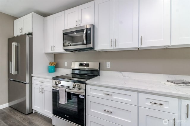 318 Mill Ave SE, Orting, WA 98360 - kitchen featuring appliances with stainless steel finishes, dark wood-style flooring, white cabinets, and light stone countertops