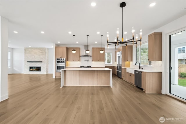 8517 137th Ave SE Unit 1, Newcastle, WA 98059 - kitchen featuring wall chimney exhaust hood, stainless steel appliances, open floor plan, a chandelier, and light countertops