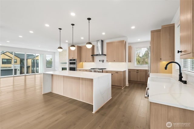 8517 137th Ave SE Unit 1, Newcastle, WA 98059 - kitchen featuring wall chimney range hood, a large island, recessed lighting, light wood-type flooring, and tasteful backsplash