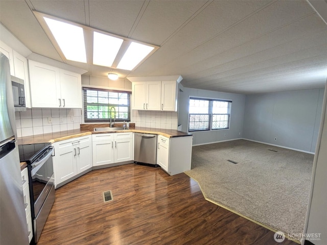 201 Union Ave SE Unit 92, Renton, WA 98059 - kitchen featuring appliances with stainless steel finishes, white cabinetry, dark wood-type flooring, tasteful backsplash, and open floor plan