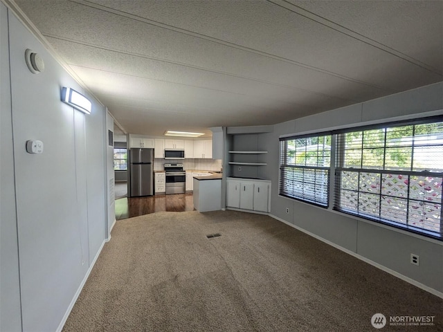 201 Union Ave SE Unit 92, Renton, WA 98059 - kitchen featuring appliances with stainless steel finishes, dark carpet, white cabinets, plenty of natural light, and a textured ceiling