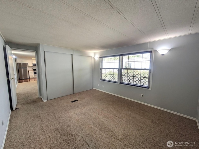 201 Union Ave SE Unit 92, Renton, WA 98059 - unfurnished bedroom with freestanding refrigerator, carpet floors, a textured ceiling, and a closet