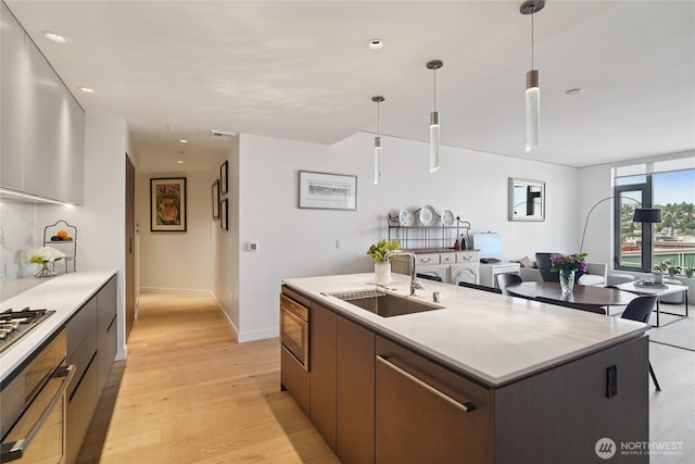 2510 6th Ave Unit 1010, Seattle, WA 98121 - kitchen featuring a center island with sink, modern cabinets, light countertops, wall oven, and light wood-style floors