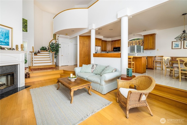 33571 Cliff Rd, Mount Vernon, WA 98274 - living room with decorative columns, light wood-style floors, a towering ceiling, a fireplace with flush hearth, and stairway