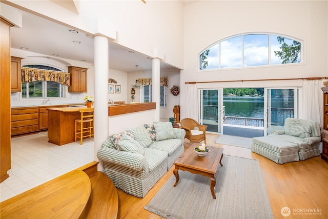 33571 Cliff Rd, Mount Vernon, WA 98274 - living area featuring ornate columns, light wood-style flooring, a high ceiling, and a water view