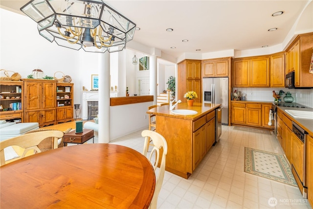 33571 Cliff Rd, Mount Vernon, WA 98274 - kitchen featuring appliances with stainless steel finishes, brown cabinetry, a center island, decorative backsplash, and a chandelier