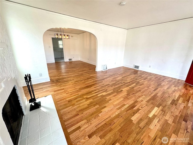 608 N Puget Sound Ave, Tacoma, WA 98406 - unfurnished living room featuring arched walkways, light wood finished floors, a fireplace, and a chandelier