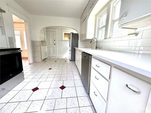 608 N Puget Sound Ave, Tacoma, WA 98406 - kitchen with stainless steel appliances, arched walkways, white cabinetry, light countertops, and tasteful backsplash