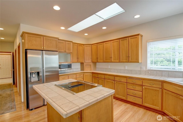 1218 Alpine View Dr, Mount Vernon, WA 98274 - kitchen with stainless steel appliances, tile counters, light wood finished floors, a skylight, and a kitchen island