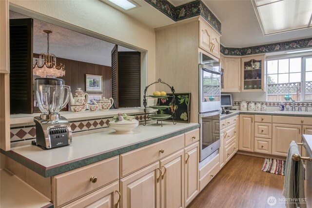605 Lee Ave, Aberdeen, WA 98520 - kitchen with stainless steel double oven, dark wood-style floors, light brown cabinets, tasteful backsplash, and glass insert cabinets