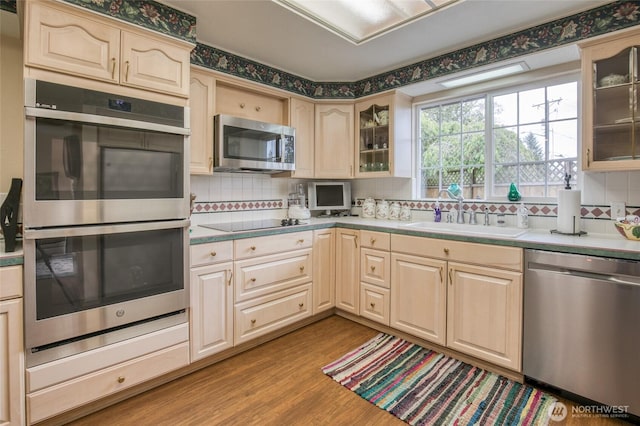605 Lee Ave, Aberdeen, WA 98520 - kitchen featuring appliances with stainless steel finishes, decorative backsplash, light wood-style flooring, glass insert cabinets, and light brown cabinetry