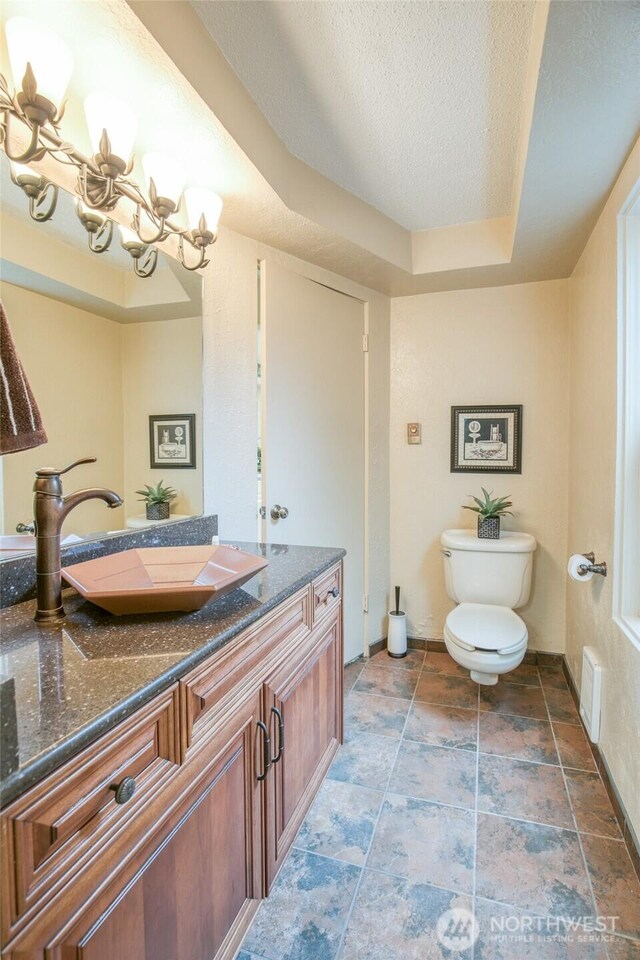 605 Lee Ave, Aberdeen, WA 98520 - half bath featuring vanity, a chandelier, stone finish floors, a tray ceiling, and a textured ceiling
