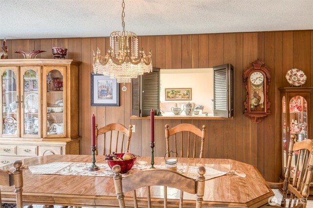 605 Lee Ave, Aberdeen, WA 98520 - dining space featuring wood walls, a textured ceiling, and a chandelier