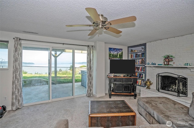 96 Kim Ct, Steilacoom, WA 98388 - living area with a textured ceiling, a ceiling fan, a brick fireplace, and carpet