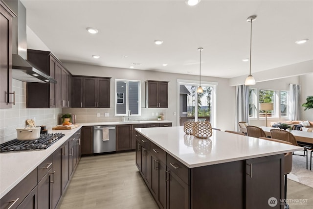 3828 98th Avenue Ct E Unit 10, Edgewood, WA 98371 - kitchen featuring appliances with stainless steel finishes, wall chimney range hood, dark brown cabinets, a center island, and decorative backsplash