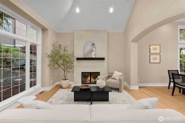 19221 SE 25th St, Sammamish, WA 98075 - living area featuring arched walkways, wood finished floors, a tile fireplace, high vaulted ceiling, and recessed lighting