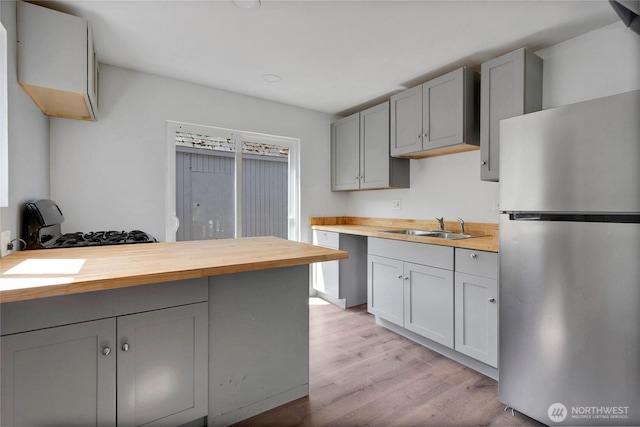 4050 E B St, Tacoma, WA 98404 - kitchen with freestanding refrigerator, butcher block countertops, gray cabinetry, light wood-style floors, and a peninsula